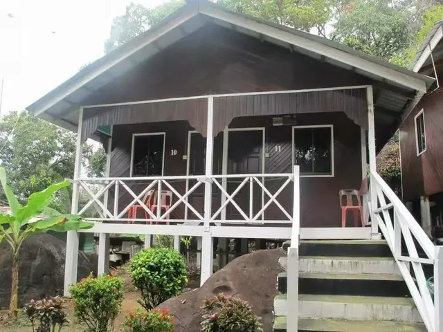 Wooden Aguna Resort chalet with a raised veranda, white railings and tropical plants
