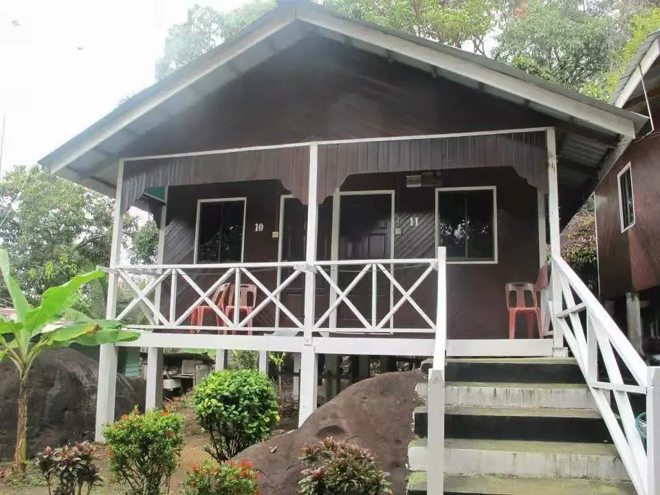 Wooden Aguna Resort chalet with a raised veranda, white railings and tropical plants