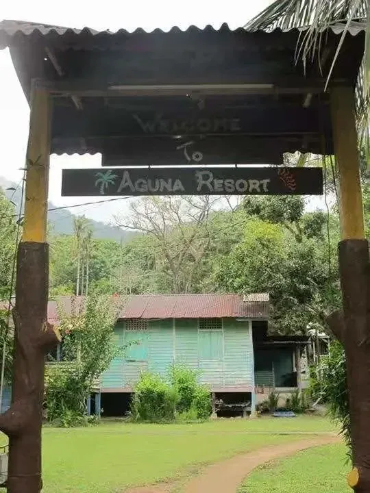 Aguna Resort entrance sign overlooking the garden and a green wooden chalet