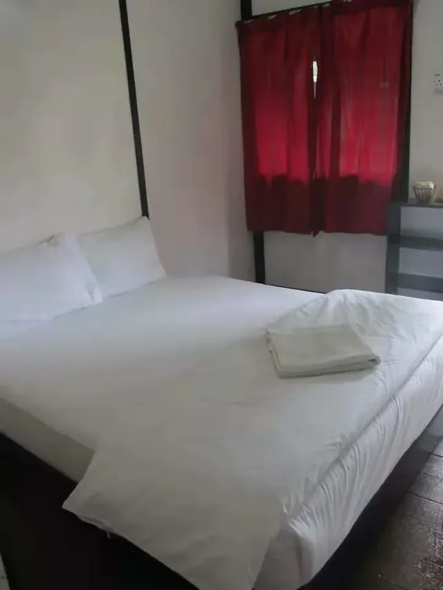 A queen bed with white linens and folded towels in an Aguna Resort room