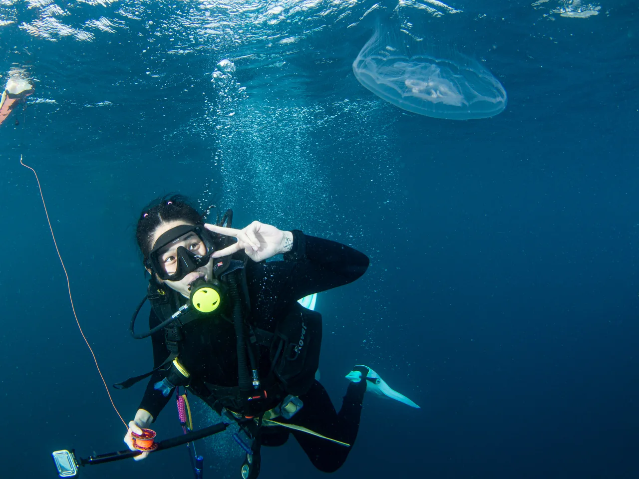 A diver beneath the sunlit surface near a jellyfish