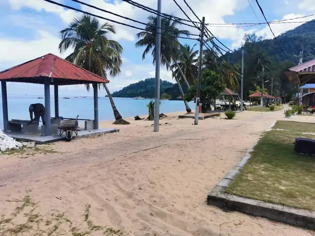 Beachfront path, palms and shaded gazebo beside the sea at Idaman Beach Holiday Resort