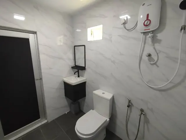 Tiled bathroom with hot-water shower, toilet and wash basin at Idaman
