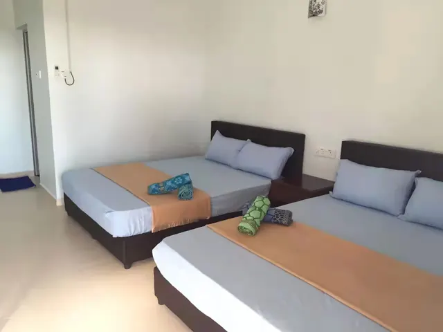 Two queen-size beds and folded towels in an Idaman deluxe quad room