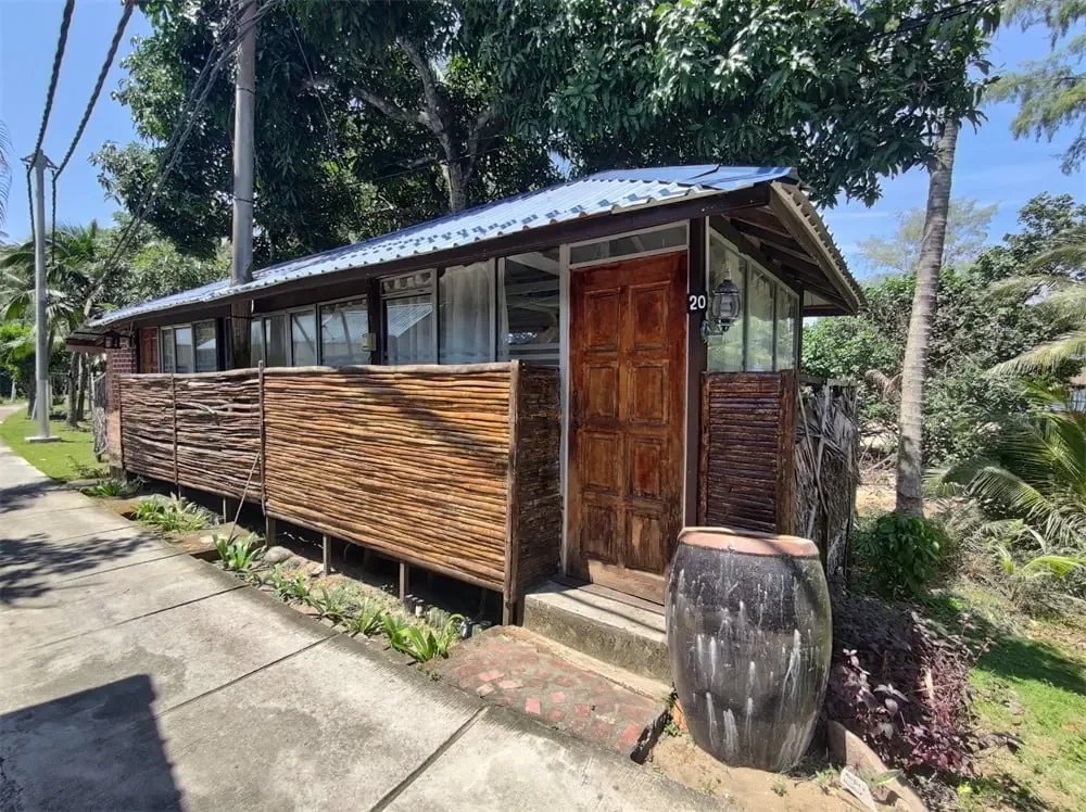 Wooden Impian Inn chalets beside a garden path and tropical trees in Kampung Genting