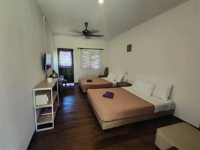 Impian Inn quad room interior with two large beds, wooden flooring and a desk
