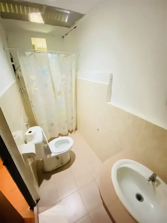 Impian Inn twin room bathroom with a basin, toilet and curtained shower area