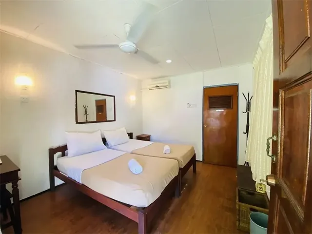 Impian Inn twin room with two single beds, wooden flooring, a ceiling fan and air conditioning