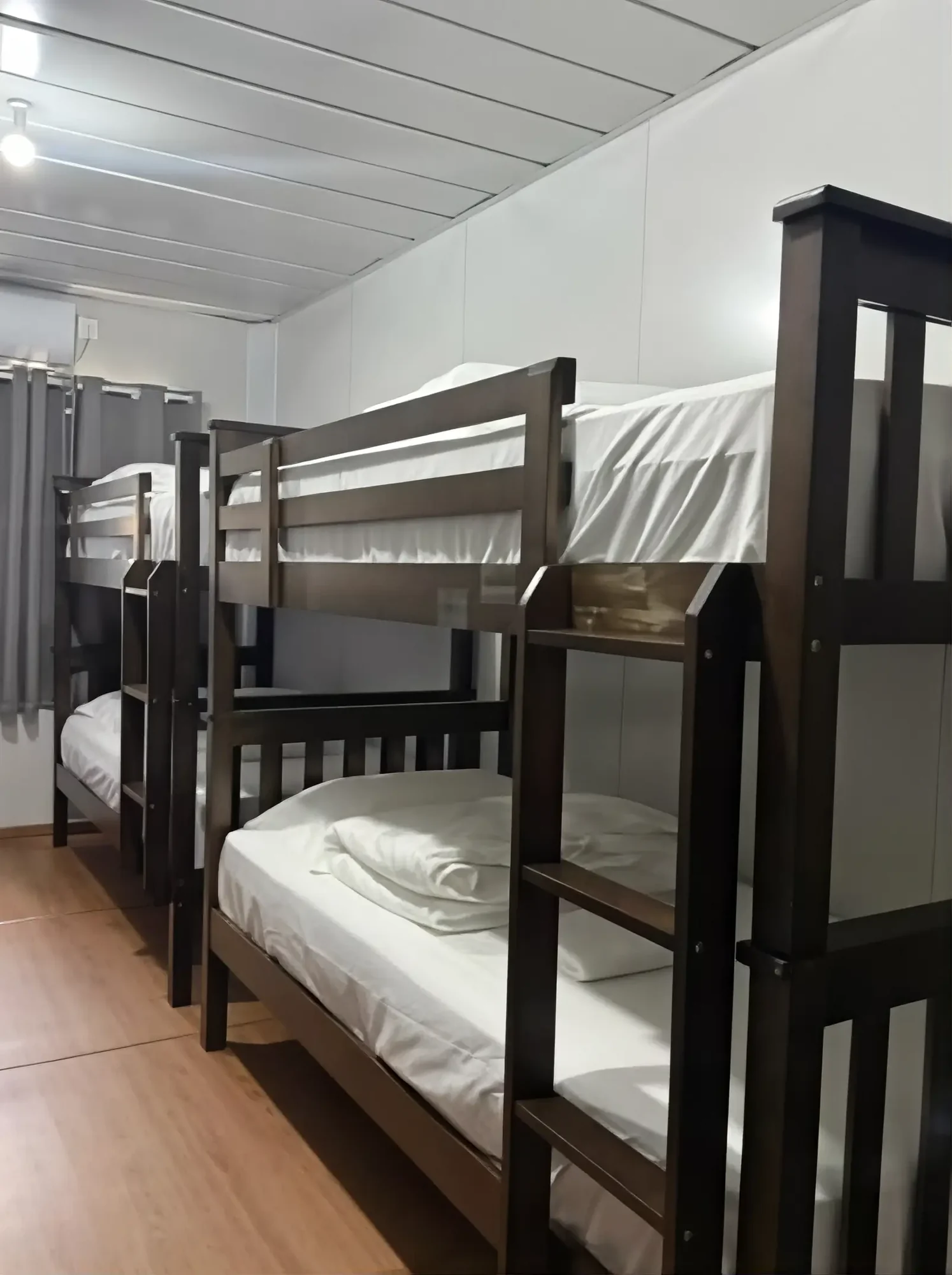 Wooden bunk beds with white linens in the TDB Tioman Resort dorm