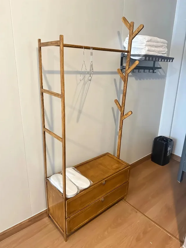 Wooden clothes rack, fresh towels and slippers in a deluxe room